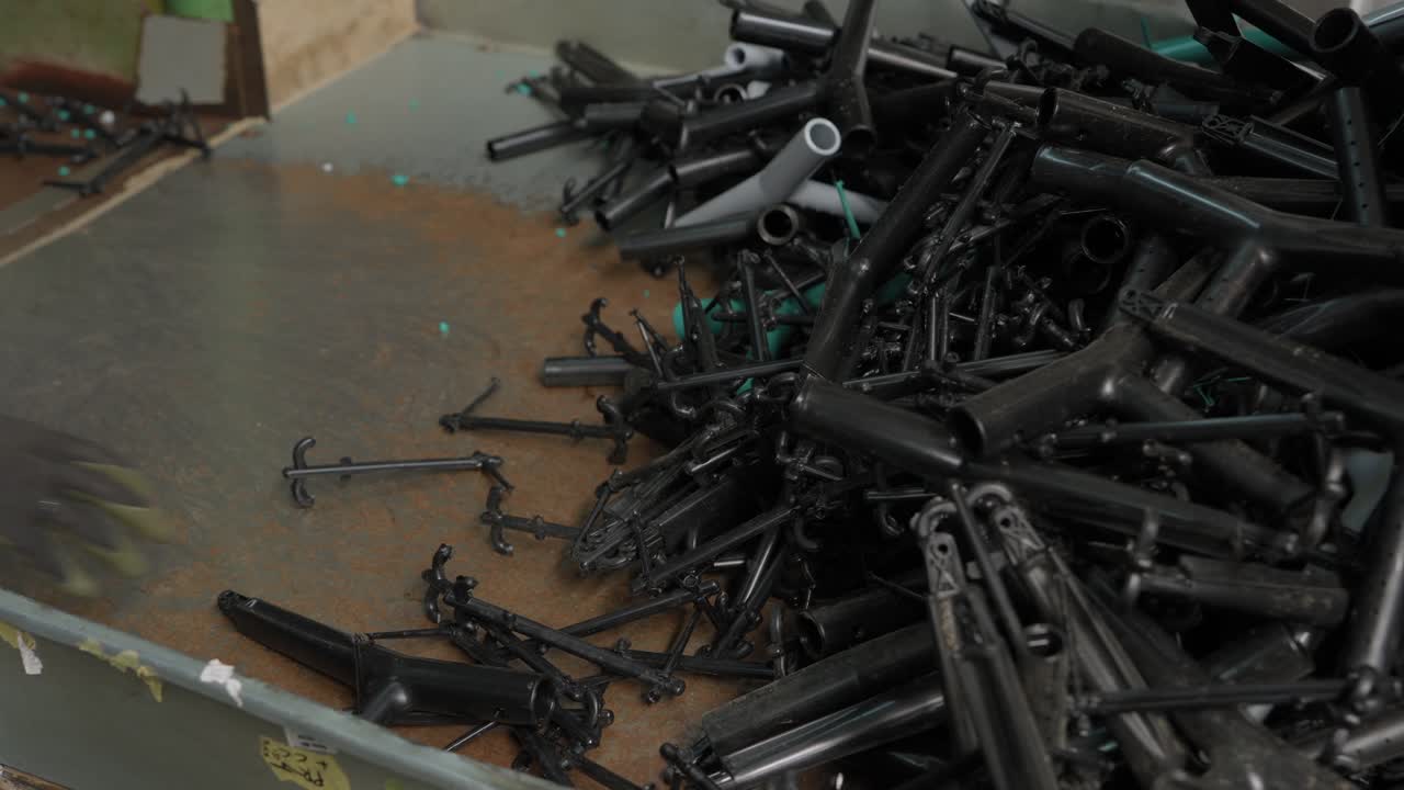 Large bin filled with tangled black plastic chair frames and parts ready for recycling and shredding
