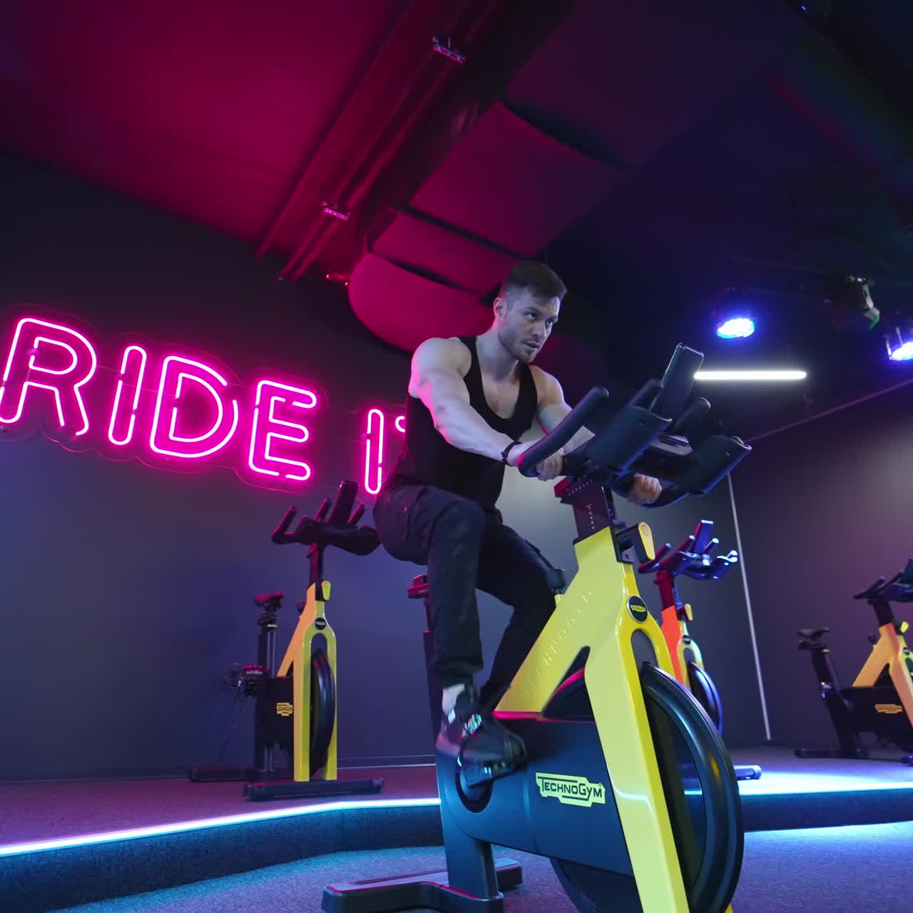 Man doing cardio workout cycling bikes. Footage of sportsman riding bike at the gym