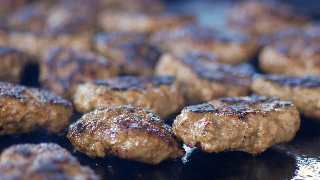 Close up of ground beef patties grilling on a flat top grill