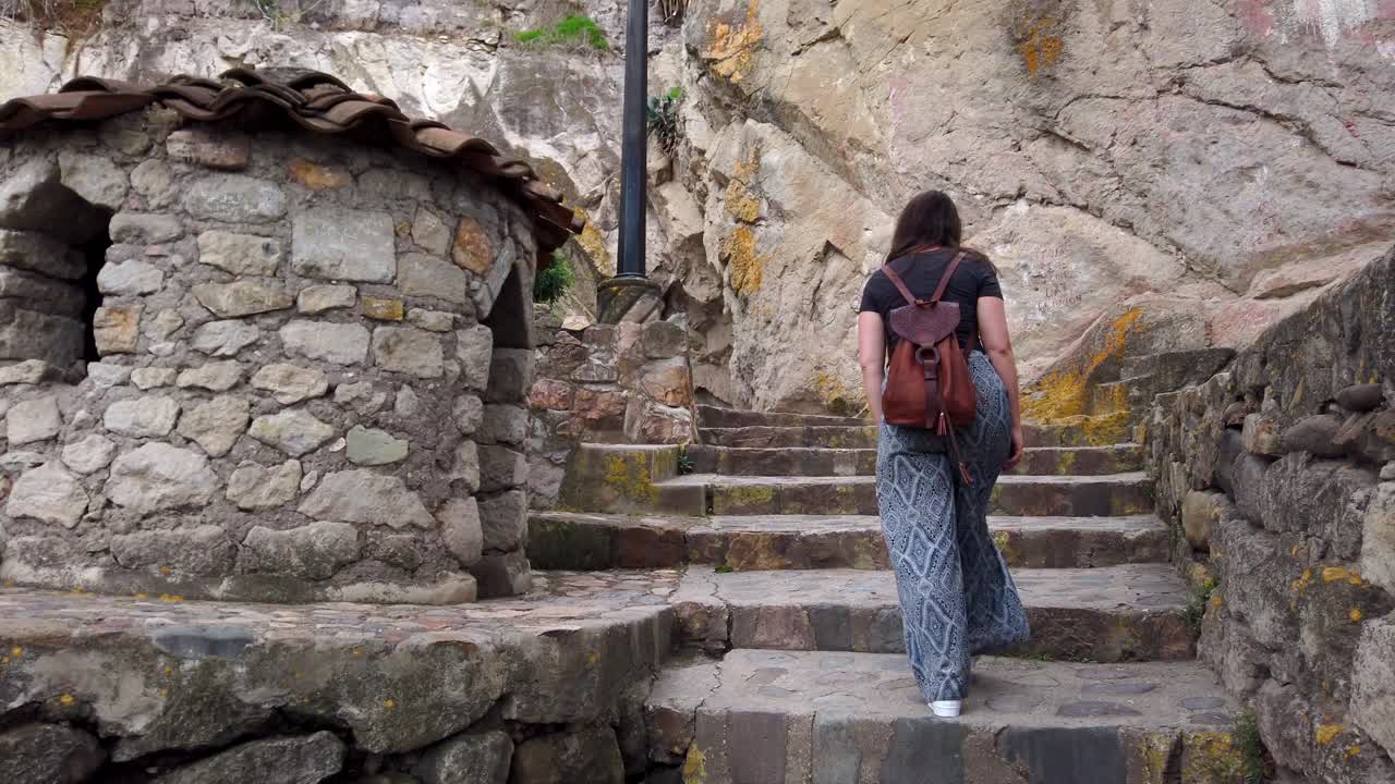 vista posterior de una turista con mochila subiendo una escalera de piedra en el cerro santa apolonia en cajamarca, perú
