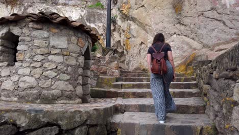 back view of a female tourist with backpack climbing up a stone stairway at cerro santa apolonia in cajamarca, peru