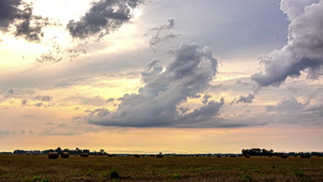 Stormy-clouds-pass-over-agricultural-fields-after-harvesting-wheat-grains-in-stacks