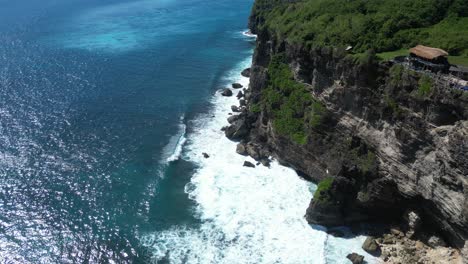 waves crashing into the shores of uluwatu, bali, indonesia on a hot summers afternoon