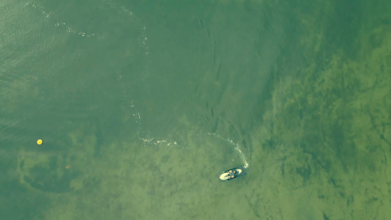 Aerial shot motorboat rotate on clear calm green water sea, Rewa in Poland