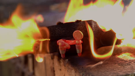 a blacksmith uses gas welding to melt a brass saxophone, resulting in destructive sparks and brightly coloured flames