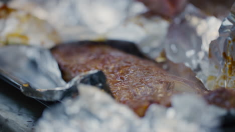 low angle view of foil being peeled from steaming bbq ribs