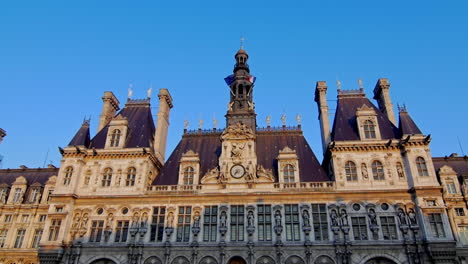 ornate historic parisian building with a central clock tower and steep slate rooftops under a clear blue sky