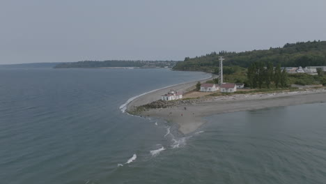 slow aerial push towards the west point lighthouse with windy conditions pushing water against the shore in seattle, wa