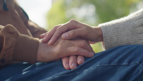 holding hands of elderly man in wheelchair