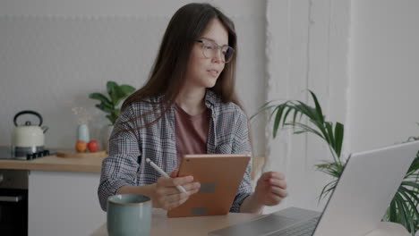 young woman working from home with laptop and tablet