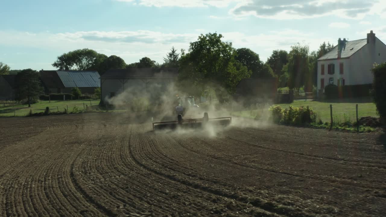 Tomada aérea cinematográfica de trator na paisagem francesa, árvores, estradas e vilarejos