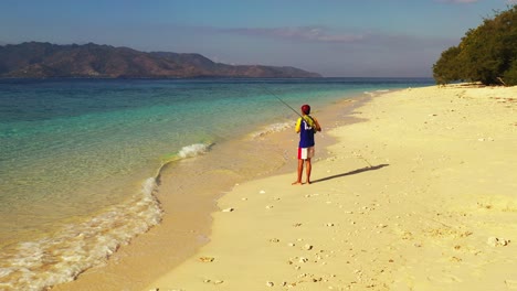 Viti-Levu-Island,-Fiji---Young-Fisherman-On-the-Seashore-Holding-Fishing-Tackle-and-Trying-to-catch-a-Fish---Summer-Activities---Wide-Shot