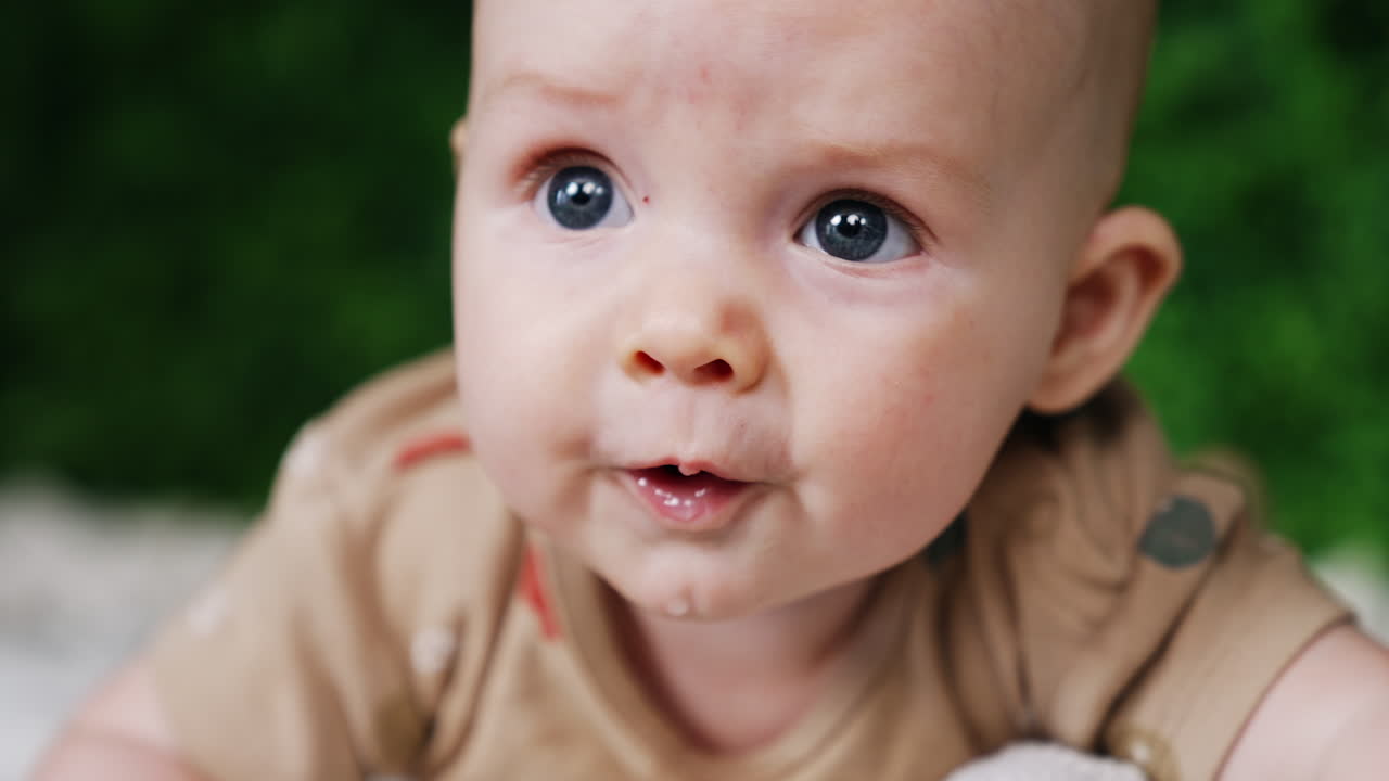 Face of a sweet little Caucasian infant. Close up. Lovely grey-eyed baby looking up with surprise.