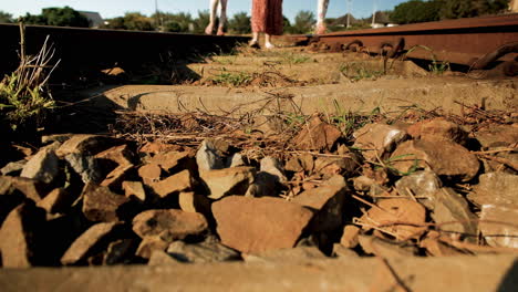 mom helps twins to balance while walking on railroad tracks