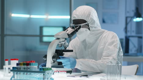 Black-Doctor-in-Protective-Suit-Working-with-Microscope-in-Lab