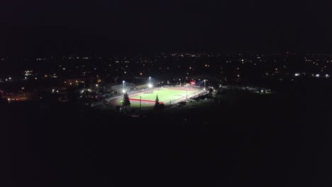 4k Drone shot of football stadium at night with lights on
