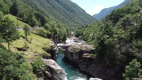 vuelo aéreo lento del río natural entre rocas y montañas verdes en suiza