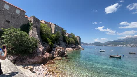 Eine-Junge-Dame,-Die-Ein-Foto-Vom-Strand-Und-Den-Wänden-Des-Berühmten-Hotels-In-Montenegro-Namens-Sveti-Stefan-Macht