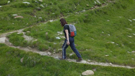 Speed-up-shot-of-woman-on-hike-walking-up-mountain-on-foot-trail,-tracking-shot