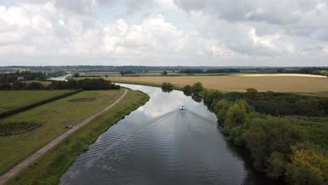 high aerial drone video catches up with a river boat sailing along the river trent in nottinghamshire