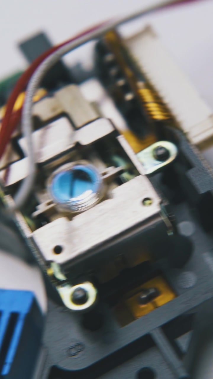 compact disk laser head and little crocodile clamps lie on clean white surface extreme close view