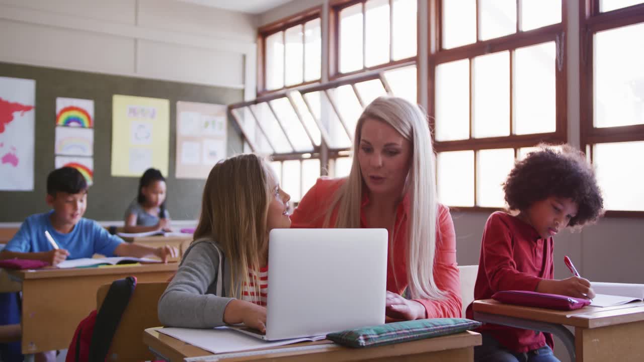 maestra y niña usando computadora portátil en clase en la escuela