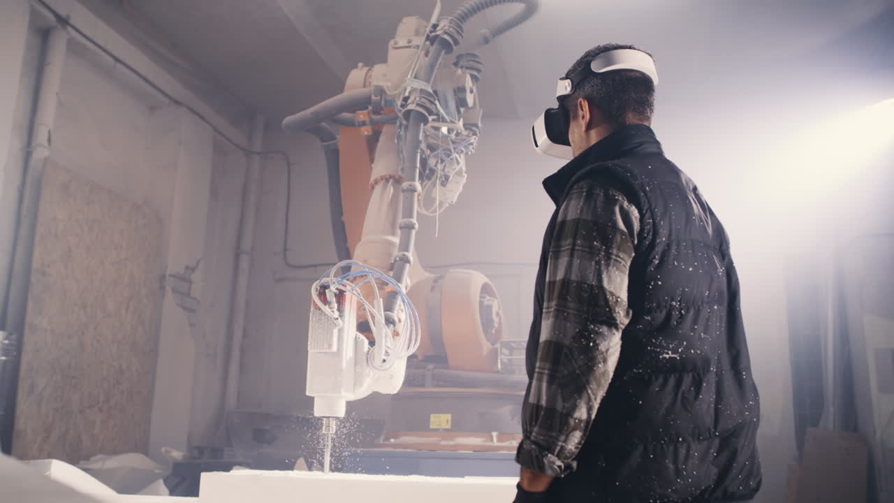 Worker using VR headset observing industrial robot in a factory