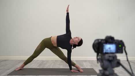 yoga em casa. mulher jovem a explicar uma pose, a gravar um vídeo tutorial.