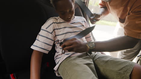 dad fastening child safety seat belt and then closing the car door