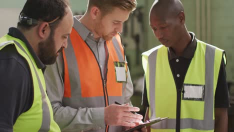 two caucasian and an african american male factory worker at a factory in discussion