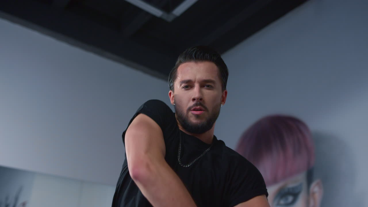 매력적인 댄서가 현대 수업에서 손을 들어 올리고 젊은 남자가 실내에서 춤을 추고 있습니다.