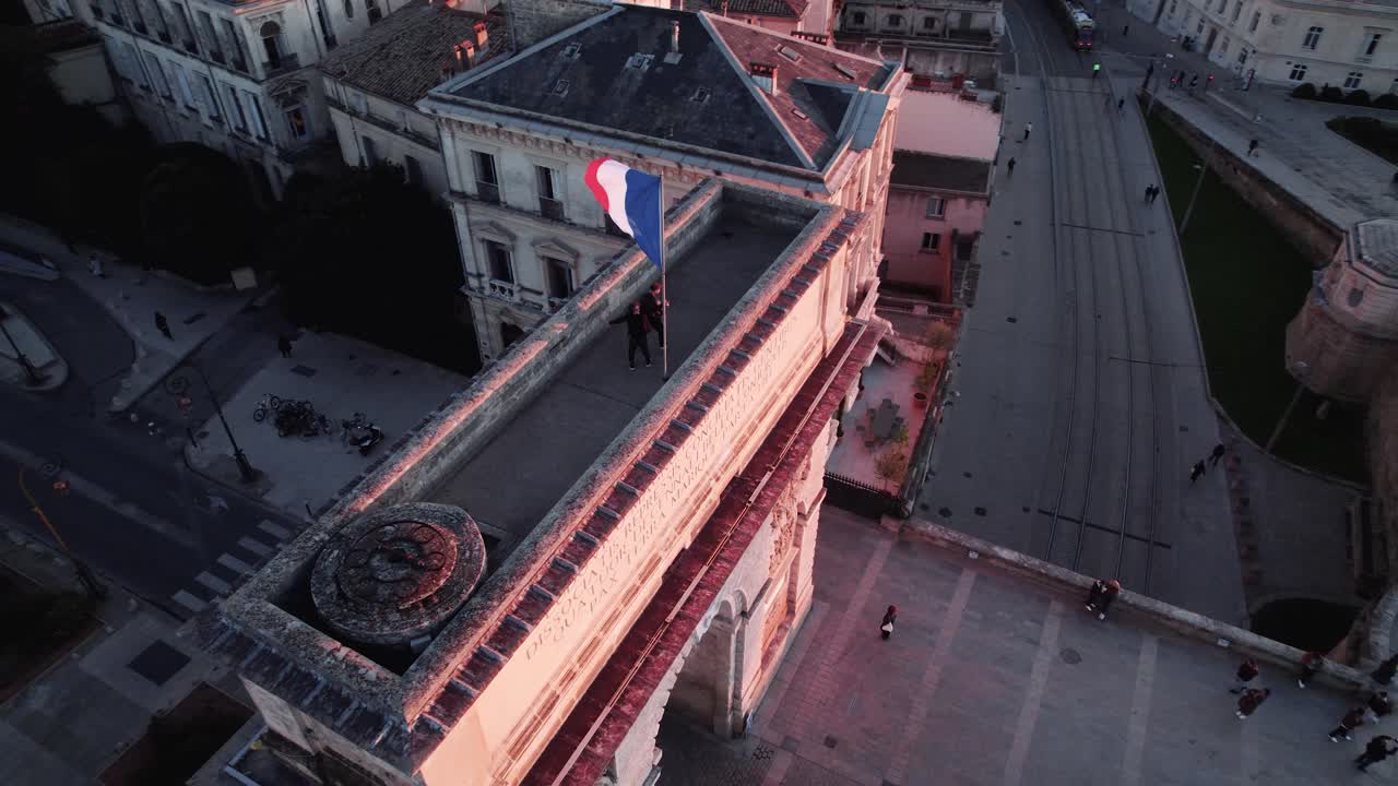 Aerial - Arc de Triomphe Montpellier at sunset with surrounding streets and buildings