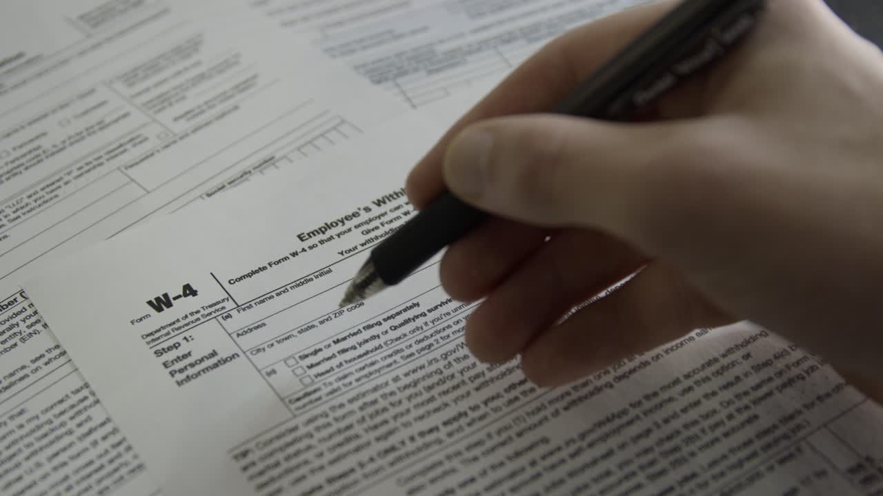 Person filling out a W-4 form. Employment withholding certificate. Person filling out tax form from IRS