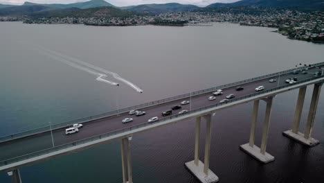 Drone-view-of-vehicles-running-on-bridge-with-speedboats-on-river