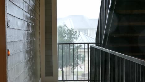 mirando desde una escalera desde el interior de un edificio a la lluvia intensa y los árboles que soplan