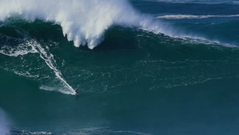 Slow-motion-of-a-big-wave-surfer-riding-a-crazy-big-monster-wave-in-Nazaré,-Portugal