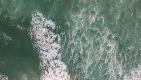 una perspectiva aérea mirando directamente al océano con olas rodando en 2