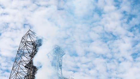 white steam on sky background. metal construction of a large industry. harmful smoke releasing into the air from grain dryer. ecological problems