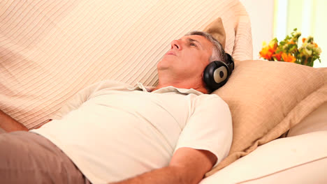 Man-lying-on-sofa-listening-to-music-with-headphones