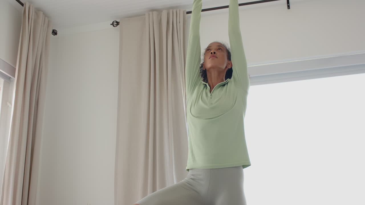 woman practicing yoga at home, balancing in tree pose