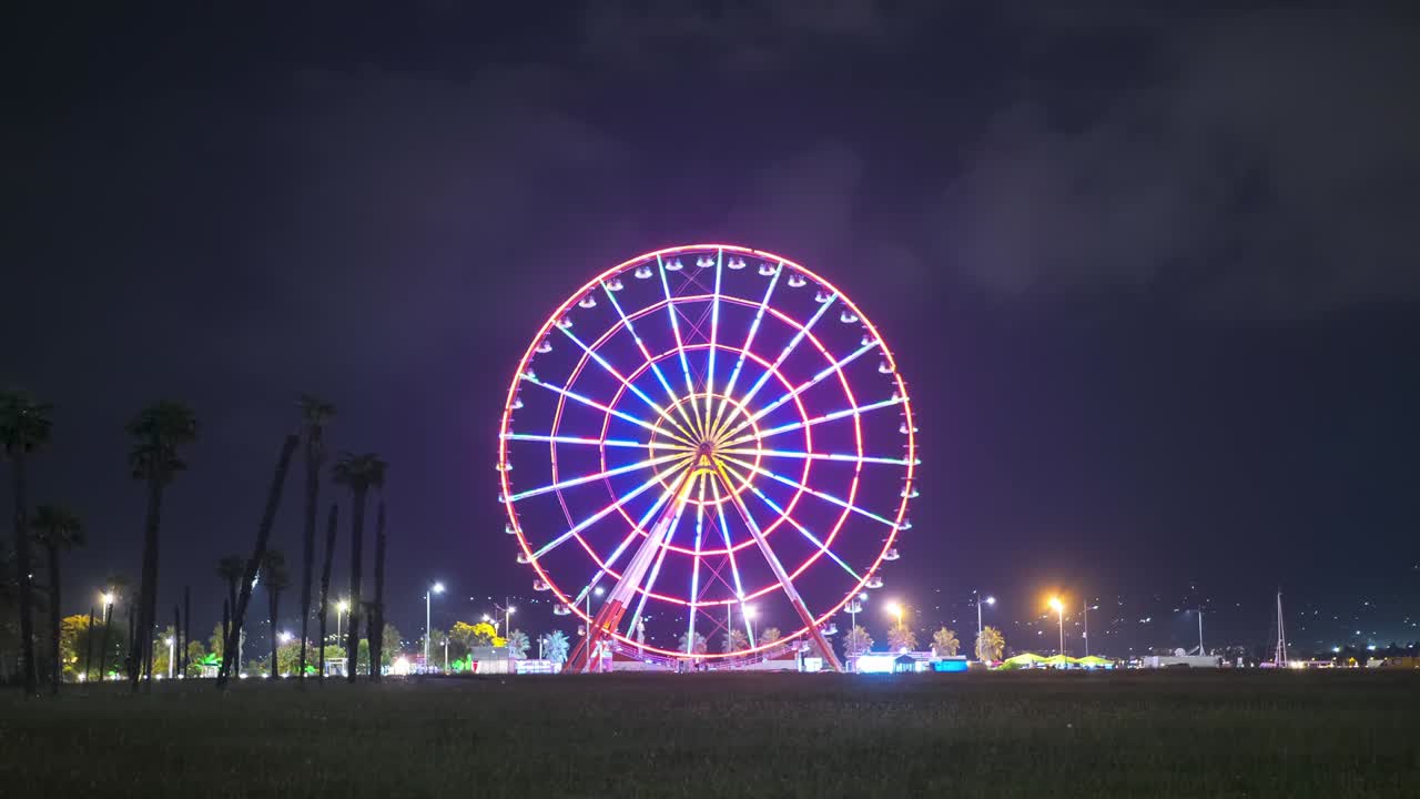 Ferris Wheel Spins at Night with Colored Lights