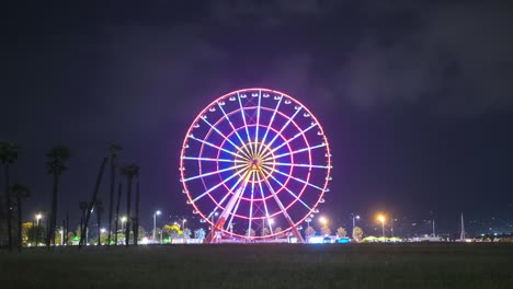 la rueda gigante gira por la noche con luces de colores