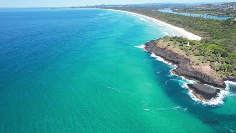 Aerial view of a beautiful coastline with turquoise water, beach, and lighthouse