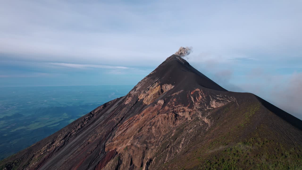 A breathtaking drone shot captures the active Volcán de Fuego in Guatemala, with a plume of ash and gas rising from its summit