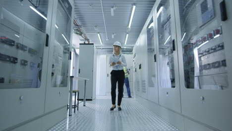female engineer inspecting electrical panels in a power plant
