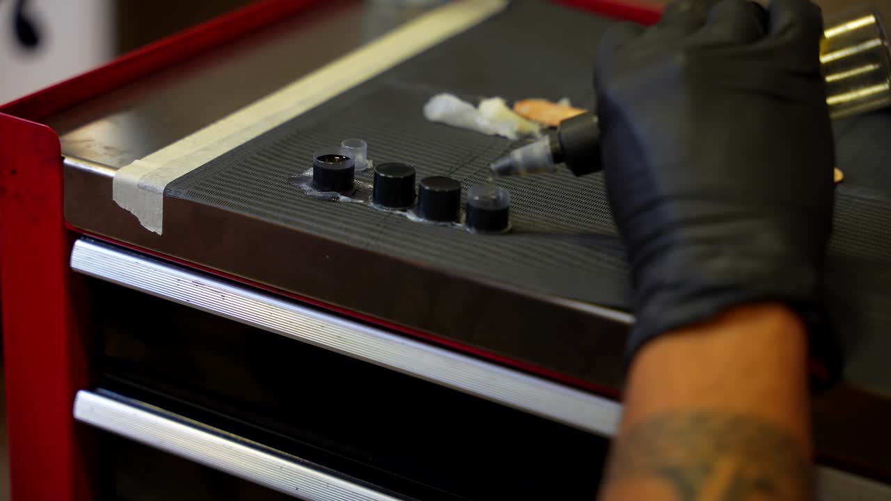 Detail close up shot of small pot of ink dropped with distilled water by a tattoo artist hand