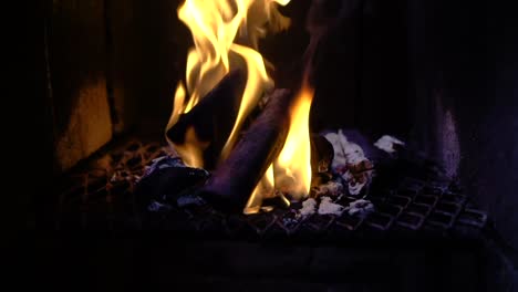 Slow motion panning shot of fire burning up in flames from small wood log and coal. close up view of a cooking tandoor grill from kitchen