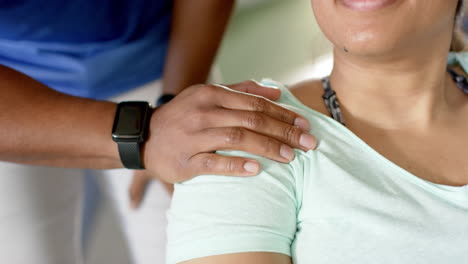 smiling woman receiving support, hand on shoulder, during disability rehab session