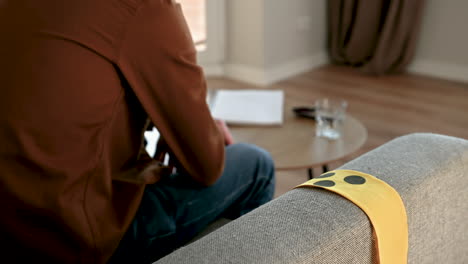 Close-Up-Of-An-Unrecognizable-Blind-Man-Sitting-On-Sofa-And-Drinking-Water