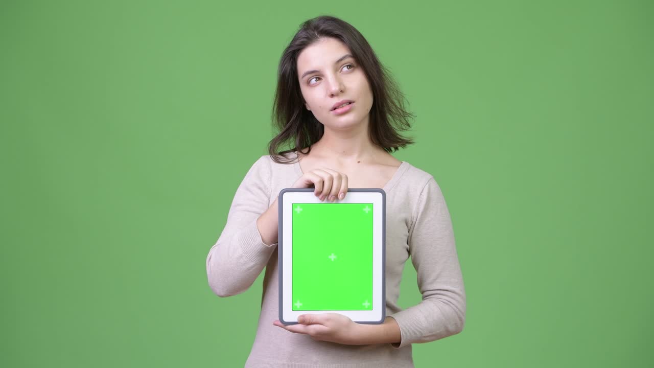 Young beautiful woman thinking while showing digital tablet